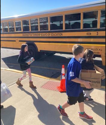 Students carrying supplies to the bus. 